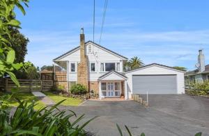 a white house with a garage in a driveway at Rest & Relax villa Whangarei 4 Bedrooms 2 Bath family home in Whangarei