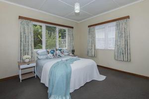 a bedroom with a bed and two windows at Rest & Relax villa Whangarei 4 Bedrooms 2 Bath family home in Whangarei