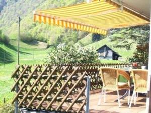un patio con mesa y sillas bajo una sombrilla amarilla en Wohnung Bemer-Rempfler - b48555, en Lungern