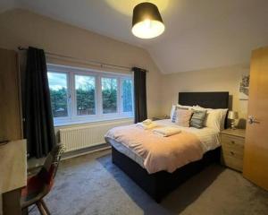 a bedroom with a large bed and a window at Spacious 4 bedroom house. in Earley