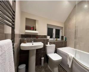 a bathroom with a sink and a toilet and a bath tub at Spacious 4 bedroom house. in Earley