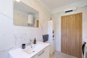 a white bathroom with a sink and a mirror at Temida in Rovanjska +26 photos