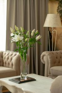 a vase of white flowers on a table in a living room at Juvena Hotel Wellness & SPA in Międzywodzie