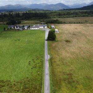a road in the middle of a field with houses at Hawthorn Self Catering Cottages in Benderloch