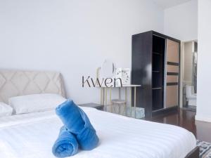 a blue stuffed animal is laying on a bed at KWEN Loft - City Centre Imago 3BR l 2BR l Studio in Kota Kinabalu