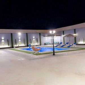 a swimming pool at night with chairs and umbrellas at الكرك زحوم in Kerak