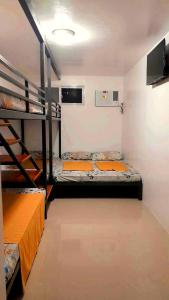 Liturs Travel Services / Homestay / Rent a Car في باكولود: غرفة بسريرين بطابقين وتلفزيون بشاشة مسطحة
