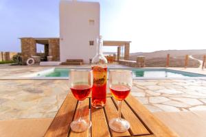 two glasses of wine sitting on a table with a bottle at Villa Poppy private pool by opus in Mikonos