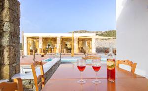 two glasses of wine sitting on a table in front of a house at Villa Poppy private pool by opus in Mikonos