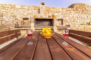 two glasses of wine and a bowl of fruit on a wooden table at Villa Poppy private pool by opus in Mikonos