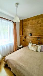 sypialnia z dużym łóżkiem i drewnianą ścianą w obiekcie Muszynka Guest House w Muszynie