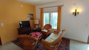 uma sala de estar com cadeiras de vime e uma televisão em Apartamento Maya, private Pool em Benissa