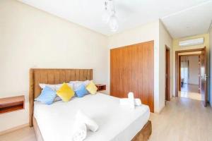 Un dormitorio con una cama blanca con almohadas azules y amarillas en Chez taux, en Marrakech