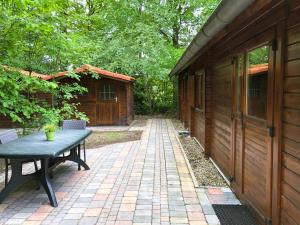 un patio con mesa y un edificio en Sfeervolle blokhut met fijne buitenruimte @ Veluwe en Epe