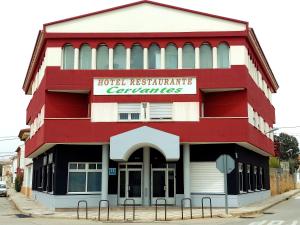 un bâtiment rouge et blanc avec un panneau sur celui-ci dans l'établissement Hotel Cervantes, à Mahora