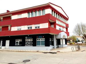 een rood-wit gebouw op de hoek van een straat bij Hotel Cervantes in Mahora