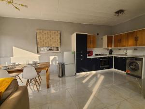 a large kitchen with a table and a refrigerator at Remarkable 3-Bed House in Freetown in Freetown