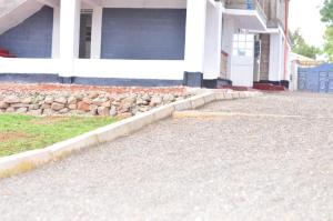 a house with a stone wall in front of a driveway at Emerald Gardens Airbnb in Kitale