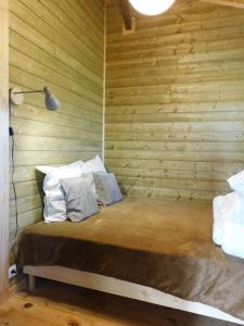 1 dormitorio con pared de madera y cama con almohadas en Gîte Birdy - Vue sur les Pyrénées, en Lamazère