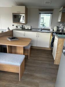 a kitchen with white cabinets and a wooden table at Ataraxia - Ocean Edge Resort - 8 Berth Accommodation in Heysham