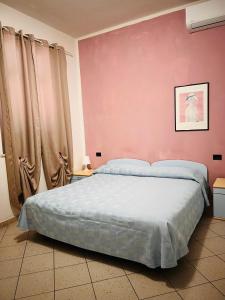 a bedroom with a large bed with a pink wall at Locanda Maria in Ameglia