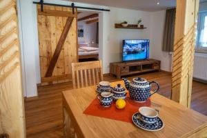 Un comedor con una mesa de madera con tazas y naranjas encima. en Ferienwohnung Mopsfidel, en Pfronten
