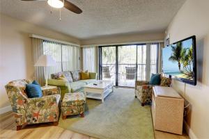 ein Wohnzimmer mit einem Sofa, Stühlen und einem TV in der Unterkunft Land's End 1-202 Bay Front in St Pete Beach