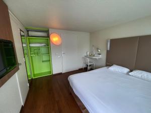 サン・ヴィクトルにあるCampanile Montluçon ~ Saint-Victorのベッドルーム(白いベッド1台、緑のドア付)