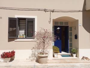 una casa bianca con piante in vaso davanti a una porta di ''A casa di Lele'' ad Avola