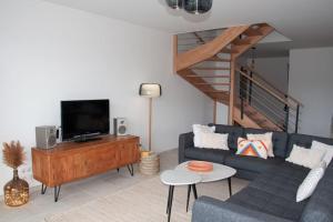 ein Wohnzimmer mit einem blauen Sofa und einem TV in der Unterkunft Duplex 6 personnes, vue panoramique sur lac in Malbuisson