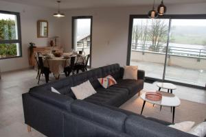 ein Wohnzimmer mit einem blauen Sofa und einem Tisch in der Unterkunft Duplex 6 personnes, vue panoramique sur lac in Malbuisson