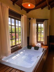 a large bath tub in a room with windows at Pousada Villa da Uva in Gramado