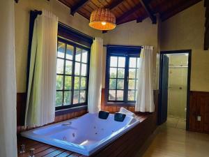 a large bath tub in a room with windows at Pousada Villa da Uva in Gramado