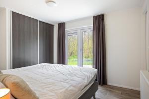 a bedroom with a bed and a large window at Chalet 41 met twee badkamers in Oosterwolde