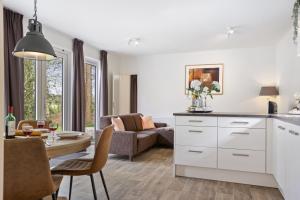 a kitchen and living room with white cabinets and a table at Chalet 41 met twee badkamers in Oosterwolde