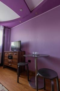 une chambre violette avec une table et deux tabourets dans l'établissement Vila Mario, à Galaţi