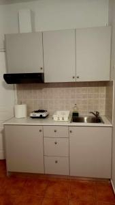 a kitchen with white cabinets and a sink at Στούντιο με θέα τη θάλασσα in Itea