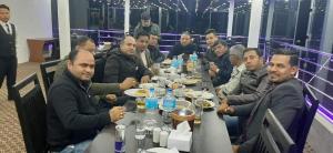 een groep mannen die aan een tafel eten bij Hotel Suryansh Pvt Ltd in Heṭauḍā