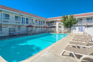 a swimming pool with chaise lounge chairs in front of a building at Motel 6-Redding, CA - South in Redding