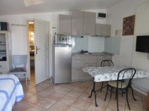 cocina con nevera, mesa y sillas en Domaine du bois gîte Marion, en Galargues