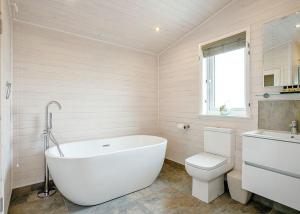 a bathroom with a white tub and a toilet at Knights Lodges in Newton Solney