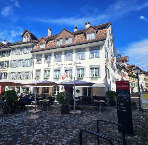 a hotel with tables and umbrellas in front of it at Hotel Taverne zur Linde in Bischofszell