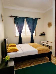 a bedroom with a bed with blue curtains and a window at Chayil Loft Mulago in Kampala