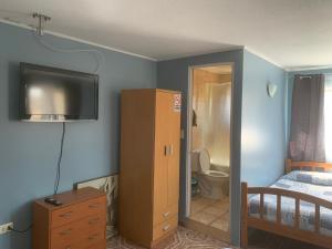 - une chambre avec un lit et une télévision murale dans l'établissement HOSTAL QUILPUE, à Quilpué