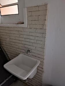 a white sink in a bathroom with a brick wall at ASSEL LOFT XAXIM in Curitiba