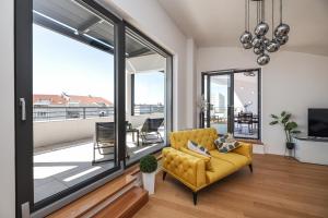 - un salon avec un canapé jaune et une grande fenêtre dans l'établissement Luxury Penthouse Berin with Rooftop Terrace and Jacuzzi, à Zadar
