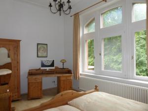 a bedroom with a bed and a desk and windows at Hotel Villa Tosca in Hannover