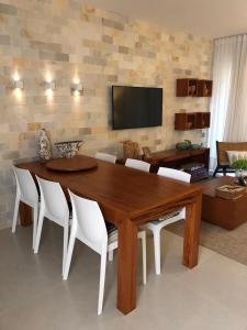 sala de estar con mesa de madera y sillas blancas en Apartamento Villa das águas resort, en Estância