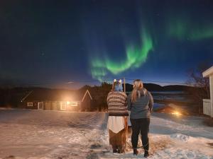 two people are looking up at the northern lights at Ulvsvåg Gjestgiveri og Fjordcamping AS in Ulvsvåg