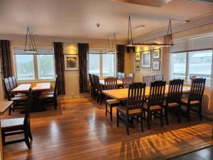 a dining room with tables and chairs and windows at Ulvsvåg Gjestgiveri og Fjordcamping AS in Ulvsvåg
